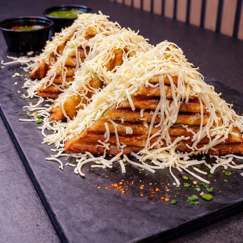 Three rows of cheesy grilled sandwiches, cut into triangles, served with two dipping sauces.